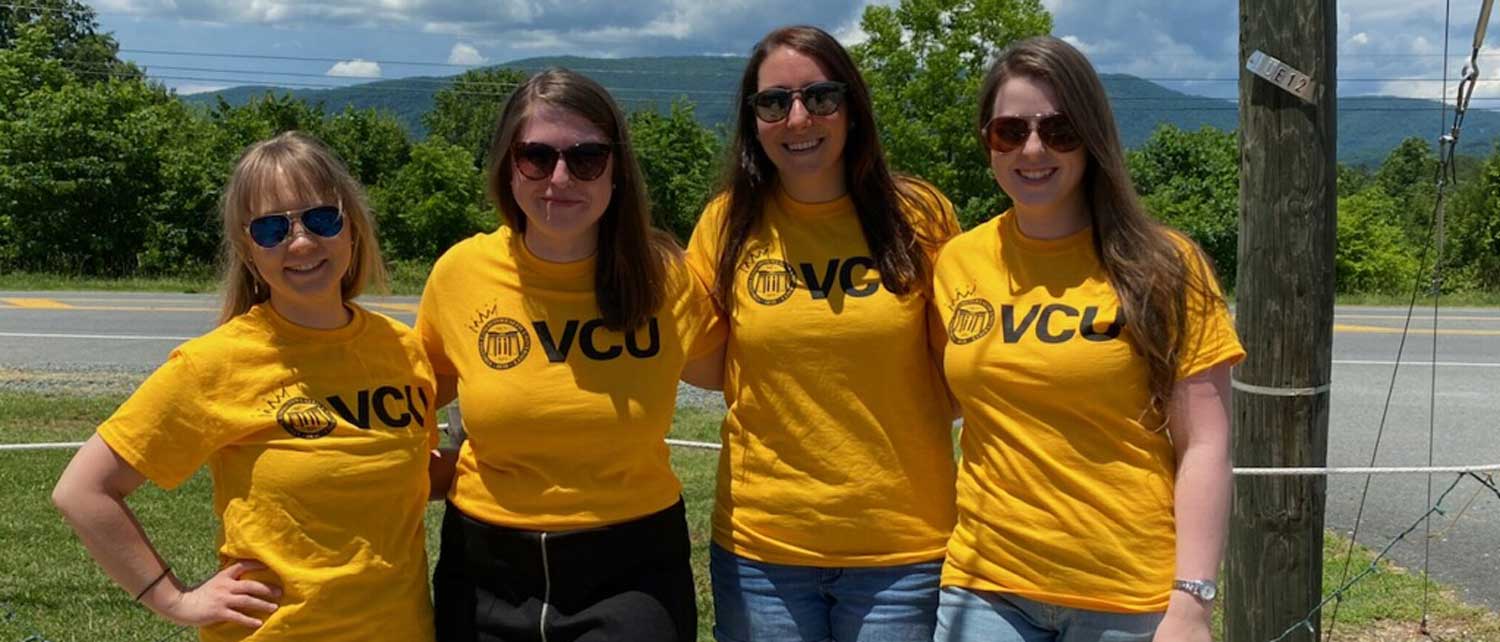 four residents wearing v.c.u. tee shirts outdoors with a mountainous backdrop