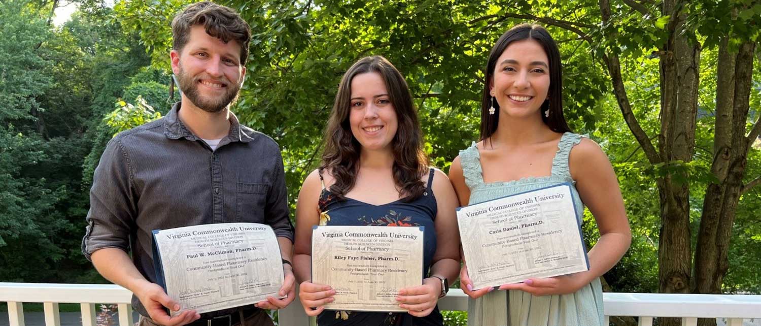three smiling residents from the class of 2022 holding their diplomas