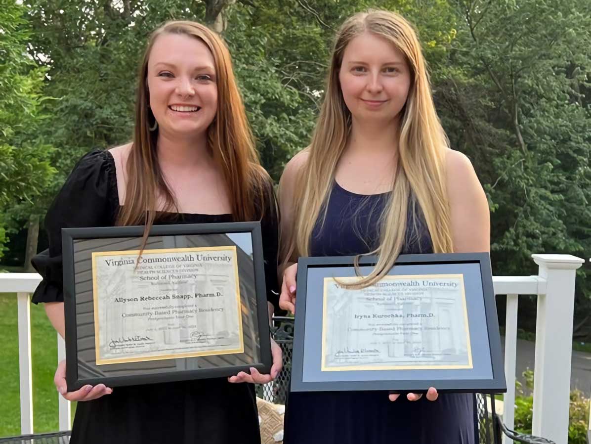 two smiling residents from the class of 2023 holding their diplomas